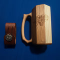 Wooden tankard with laser-engraved bee and floral design, shown alongside a leather mug strap with Celtic concho