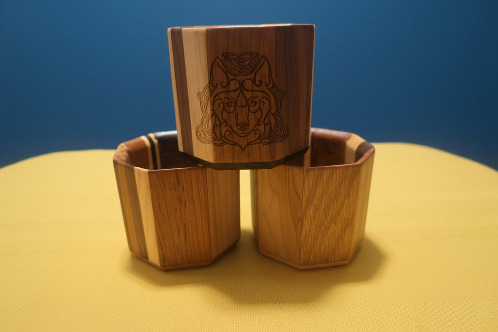 Three wooden Viking shot glasses stacked showing multi-tone hardwood grain and Celtic wolf engraving, interior view